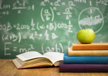 School books with apple on desk over green  school board backgroundの写真素材