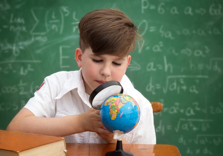 Schoolboy with globe and  loupe, interested for geographyの写真素材