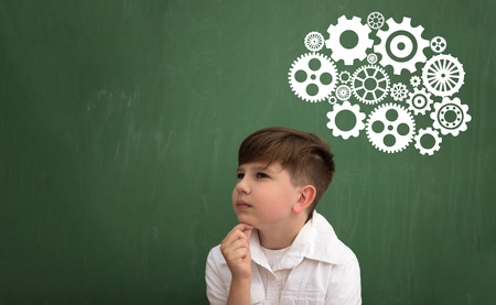 Thinking schoolboy with brainstorming shown through the mechanism of gear on blackboardの写真素材