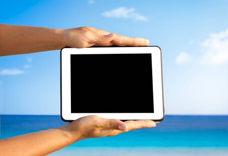 hands with digital tablet over great sea in the background, holiday conceptの写真素材