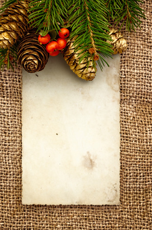 Christmas greeting card on wooden top, with holly and pine coneの写真素材