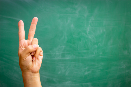 raising hand to answer over green school tableの写真素材