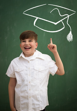 Cheerful smiling little boy on a green background. Looking at camera. School conceptの写真素材