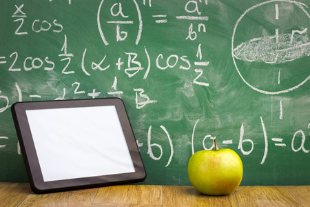 Tablet pc and apple over green  blackboardの写真素材