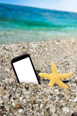 Smart phone and starfish with wavy sea on blurry backgroundの写真素材