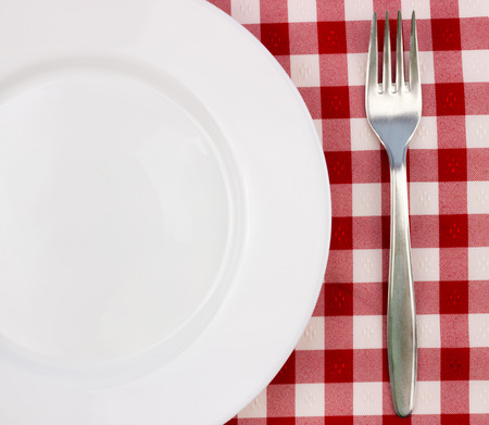 Fork and empty plate on red gingham tablecloth, top viewの写真素材