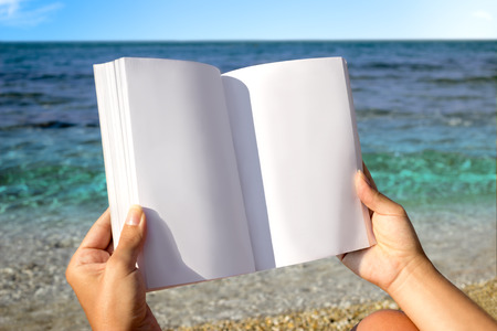 Reading book in the beach, hands holding book with blank pages, copy space for textの写真素材