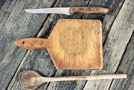 Empty chopping board with a sharp knife on a grunge wooden table in a rustic kitchen, top view with copyspaceの写真素材