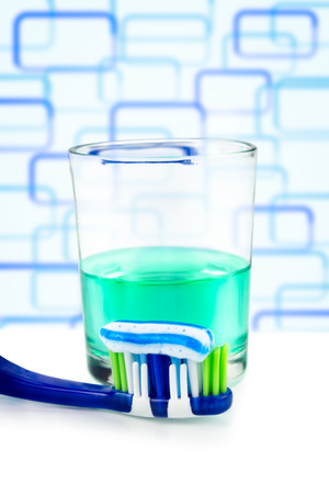 toothbrush with paste and mouthwash on glass in bathroomの写真素材