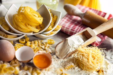 Uncooked pasta with fresh ingredients on floured surfaceの写真素材