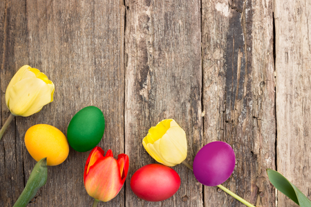 Colorful Easter eggs with tulips on wooden backgroundの写真素材