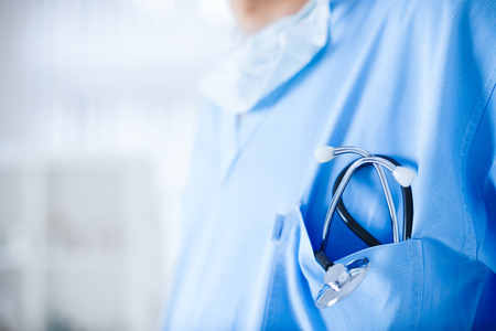 Young cardiologist with stethoscope waiting for another patientの写真素材