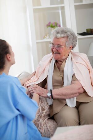 Nurse holding hands with smiling old patientの写真素材