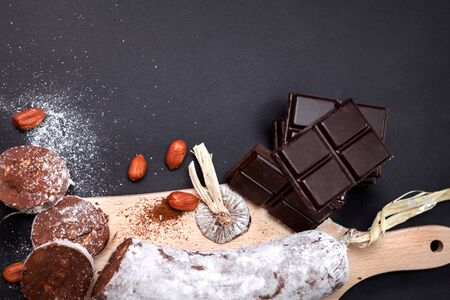 Top view of chocolate salami on chopping board with hazelnuts and chocolate tableの写真素材