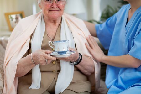 Nurse in home visit taking care of old patientの写真素材