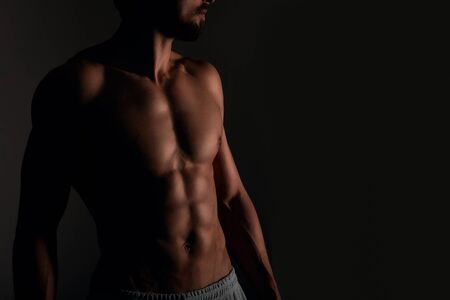 Handsome muscular man with six pack posing on black backgroundの写真素材