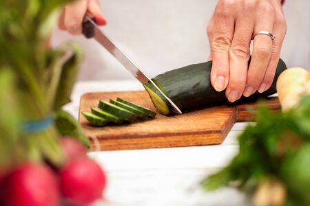 Slicing of cucumber with a knife on chopping boardの写真素材