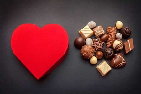Red heart shaped box with chocolate pralines on dark background, Valentines Day conceptの写真素材