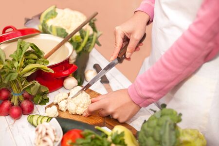 Cutting of raw cauliflower on chopping board with a knifeの写真素材