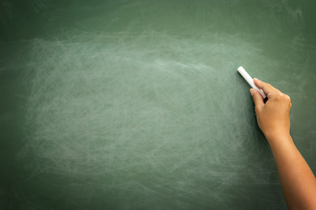 Green chalkboard with hand holding chalk, background for copy spaceの写真素材