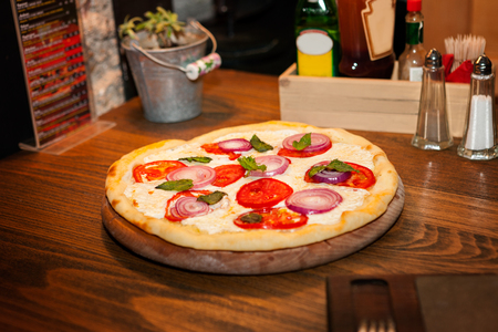 Pizza in circle shape on wooden table, delicious food served on the tableの写真素材