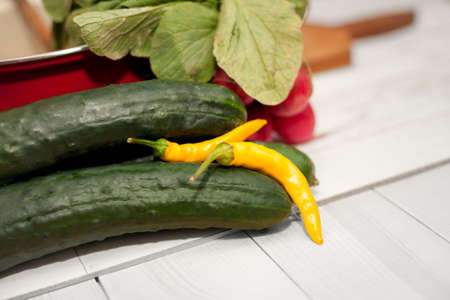 Yellow chili pepper and cucumber on kitchen tableの写真素材