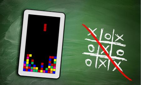 Game controller on tablet and ticktacktoe on green chalkboard, concept of modern and old way of playing gamesの写真素材