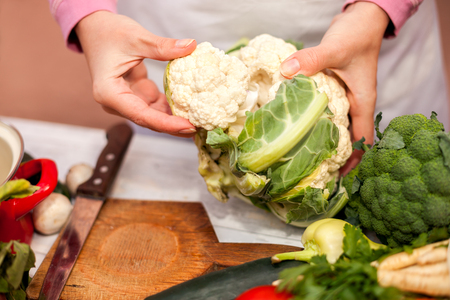 Woman holding cauliflower in her hand in the kitchenの写真素材