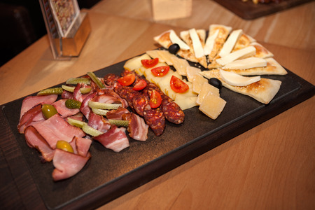 Meat appetizer on the table with cheese, pickles and olivesの写真素材