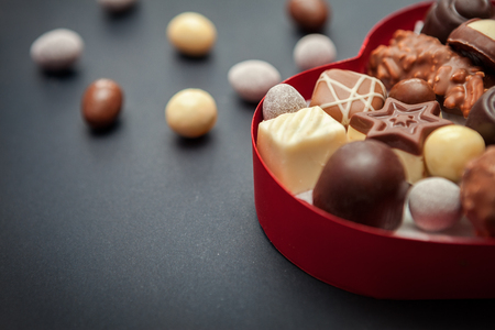 Close shot of chocolate pralines in heart shaped box on black backgroundの写真素材