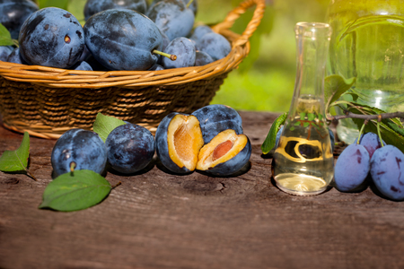 Freshly made rakia slivovitsa with cut open plums on the tableの写真素材