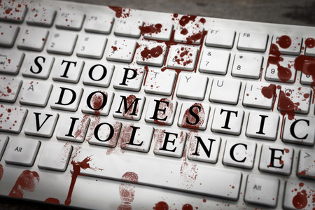 Stop domestic violence sign on bloody keyboard with bloody fingerprints, stop violence in home conceptの写真素材