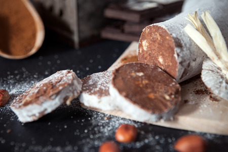 Cut pieces of chocolate salami with hazelnuts on black table backgroundの写真素材