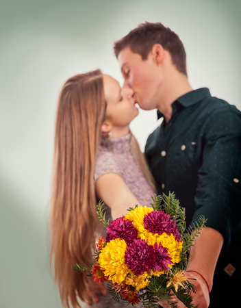 Kissing young couple holding flowers togetherの写真素材