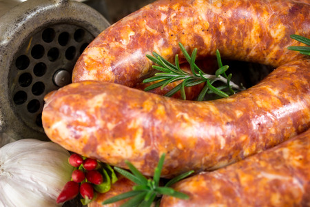 Close-up of rosemary on raw sausages and meat grinder in the backgroundの写真素材