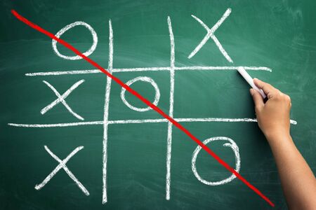 Hand drawn tic tac toe game on chalkboard, win combination drawn with red lineの写真素材