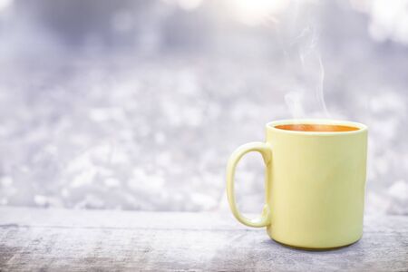 winter time with hot tea in mug on wooden surface with forest in the backgroundの写真素材