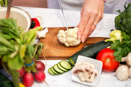 Woman cutting cauliflower with a knifeの写真素材