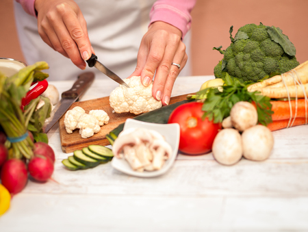 Woman is preparing to cut cauliflower with a knifeの写真素材