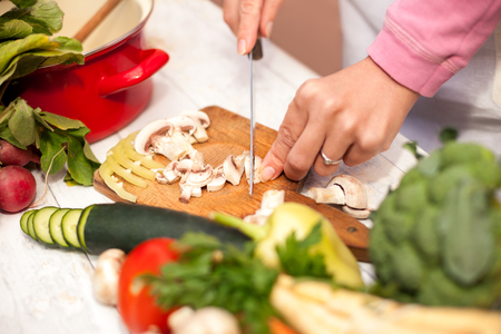 Slicing of fresh champignons in the kitchen on chopping boardの写真素材