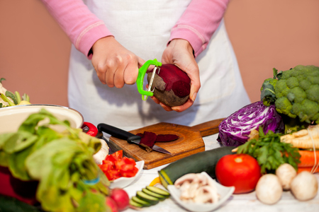 Slicing of beetroot with vegetable peeler, preparing vegetable in the kitchenの写真素材