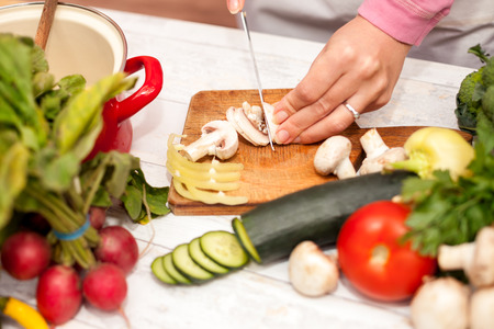 Cutting of fresh champignons in the kitchen on chopping boardの写真素材