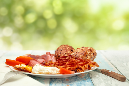 Breakfast with fried eggs, bacon, tomato and buns on a plate, Chrono diet conceptの写真素材