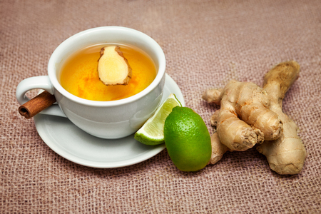 Cup with ginger tea with ginger and lime on the table