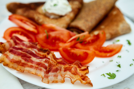 Close up of delicious breakfast on plate bacon, tomato and pancakesの写真素材