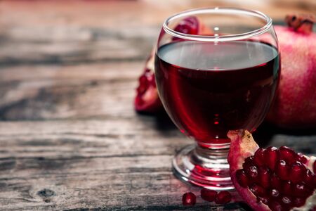 Glass with pomegranate juice on the wooden tableの写真素材