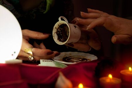 Old gypsy fortune teller holds a coffee cup for fortune tellingの写真素材