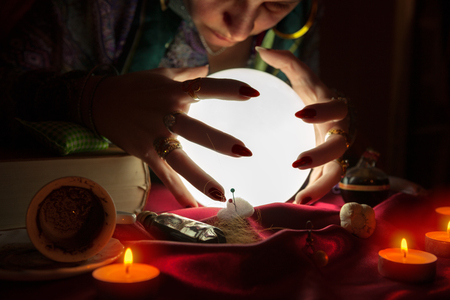 Old gypsy soothsayer looking at shiny crystal ballの写真素材