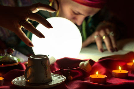 Candles and fortune teller woman who read a book in the backgroundの写真素材