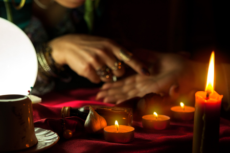 Flame from burning candles and woman who reads future from palm in the backgroundの写真素材
